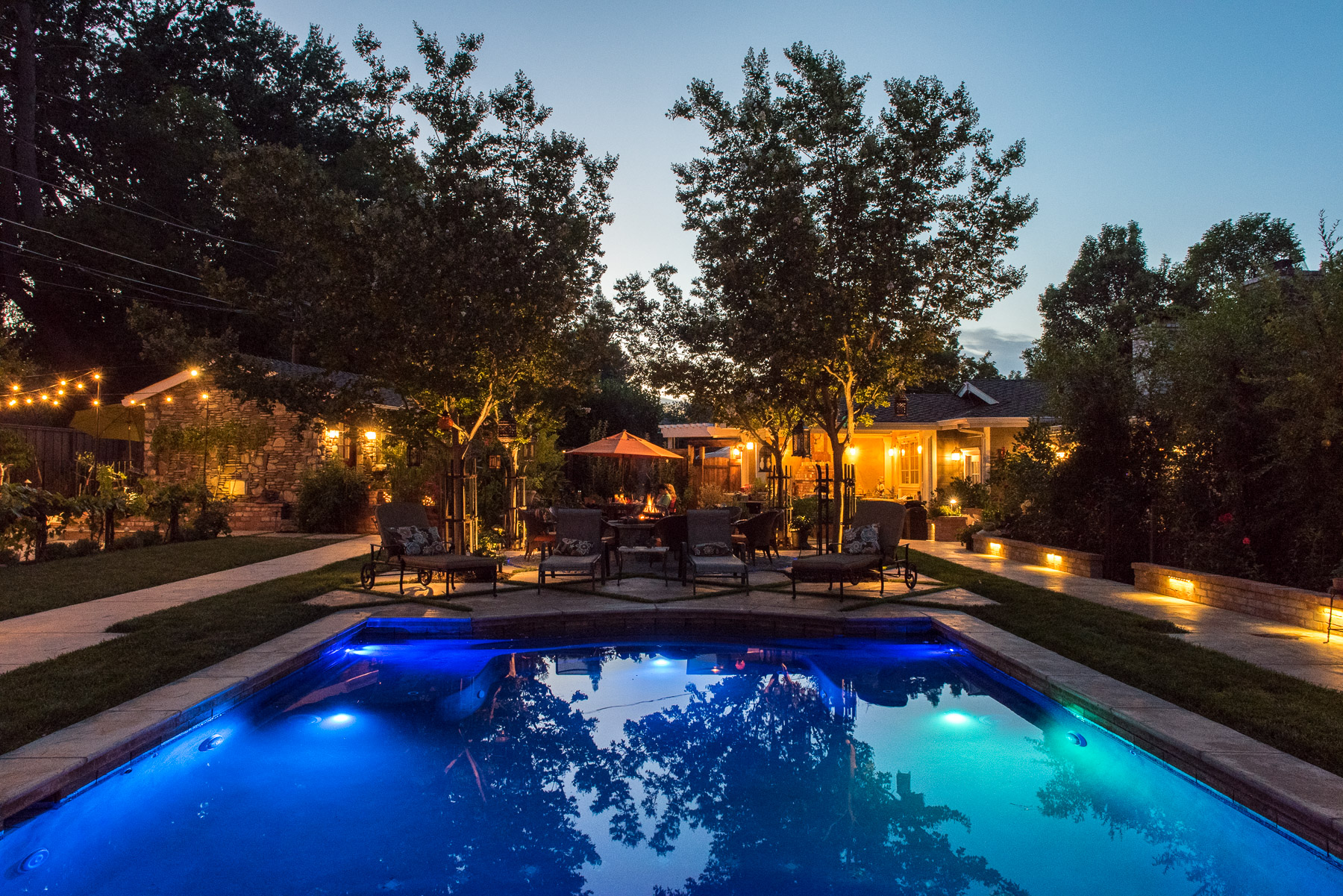 Dusk view across illuminated pool toward central seating circle